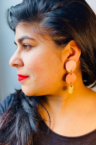 Side view of woman wearing earring with three leather circles. 