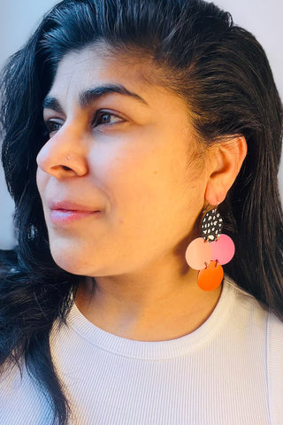 Woman wearing recycled leather earrings made with 4 recycled leather circles. 
