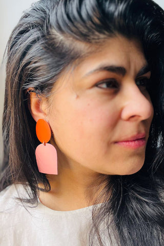 Woman wearing orange and pink leather earrings. 