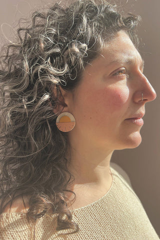 Model wearing recycled leather Helios Sunset earrings by Blisscraft. 