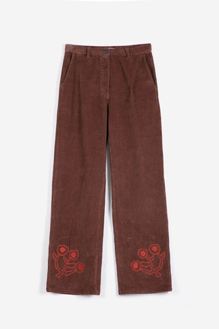 A pair of brown corduroy trousers with red embroidered floral motifs near the lower hems, displayed flat against a light gray background.