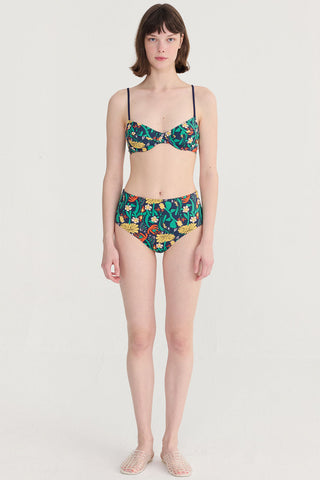 Woman wearing navy blue floral print bikini in front of white background. 