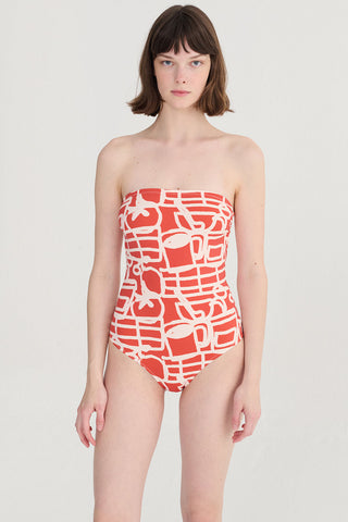 Woman wearing red and cream printed one-piece swimsuit. 
