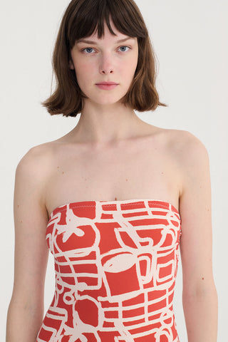 Close-up of woman wearing red and cream printed swimsuit. 