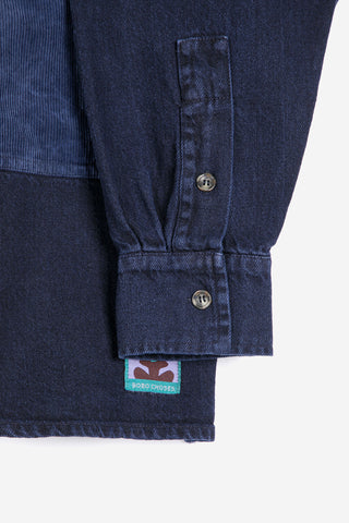 Close-up of a dark navy shirt jacket with a corduroy panel, buttoned cuffs, and a visible Bobo Choses label.