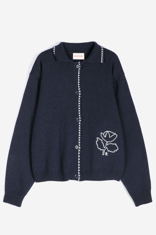 A navy blue knit cardigan sweater with white embroidered details, including a flower motif on the lower right side and white bead-like trim along the front opening and collar, shown against a plain white background.