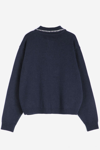 A navy blue knit sweater with a decorative white embroidery along the collar, shown from the back against a plain white background.