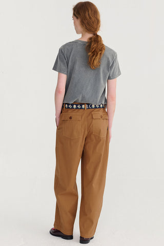 Back view of woman wearing grey t-shirt and brown loose fitting pants. 