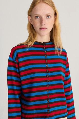 A model with blonde hair wearing a long-sleeve knit cardigan with horizontal stripes in red, blue, and black. 