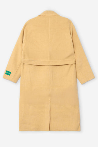 A light yellow wool coat shown from the back, featuring a belted waist and a small green brand tag on the left sleeve, set against a plain light gray background.