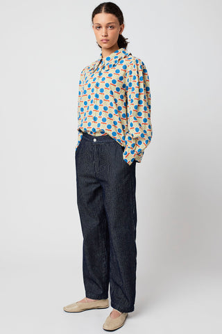 Woman wearing colourful button up shirt with navy and white pinstripe organic cotton relaxed fit jeans by Bobo Choses. 