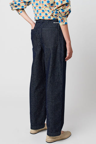 Back view of woman wearing navy and white pinstripe organic cotton relaxed fit jeans by Bobo Choses. 