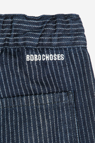 Close-up flat lay photo of waistband of navy and white pinstripe organic cotton relaxed fit jeans by Bobo Choses. 