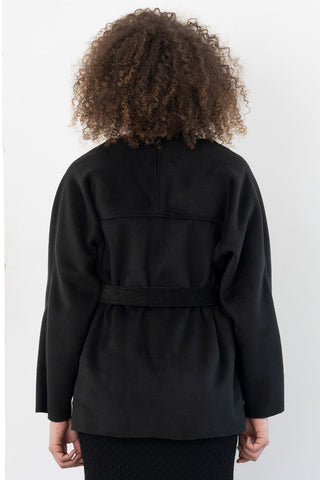 Back view of model wearing black open front belted Malcolm cardigan / jacket by Bodybag. 