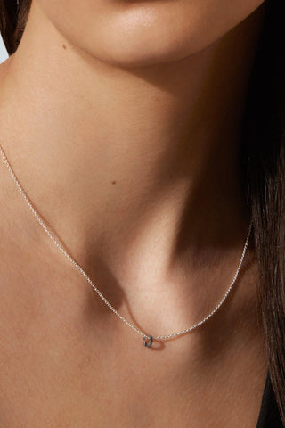 Close-up of woman wearing delicate silver chain with tiny circle pendant. 