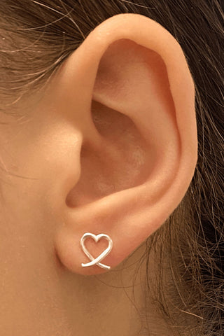 Close-up of an ear wearing a heart-shaped earring.