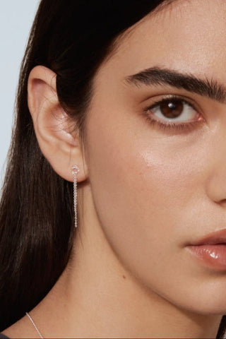 Close-up of women's face wearing sterling silver dangle earrings. 