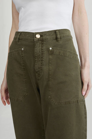 Close-up of a person wearing olive green barrel leg jeans with large front patch pockets. 