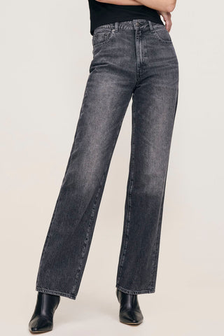 Woman in front of plain background wearing black faded straight leg Karmine jeans by DL1961. 