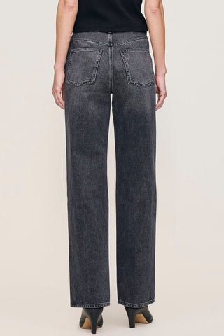 Back view of woman in front of plain background wearing black faded straight leg Karmine jeans by DL1961. 