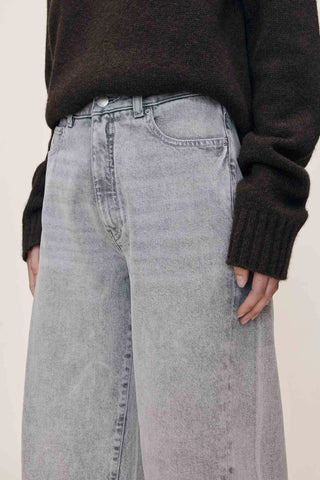 Close-up of waist of grey wash barrel cut jeans. 