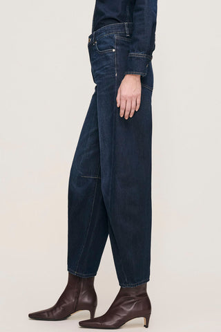 Side view of model wearing Ventura dark wash high rise barrel leg Miro Jeans by DL1961. 