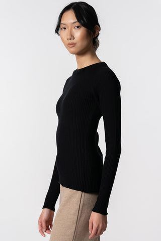 Model wearing blush black ribbed merino knit sweater by Dinadi. 