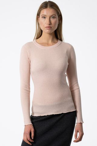 Model wearing blush pink ribbed merino knit sweater by Dinadi. 