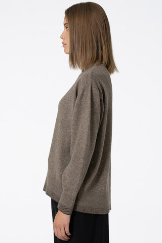 Side view of model wearing oat brown Yak wool round neck sweater by Dinadi. 