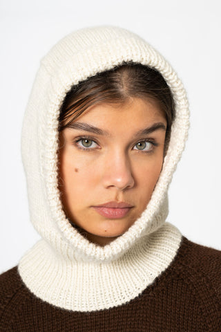 Woman in front of white background wearing brown knit sweater and ivory knit Alpaca wool Balaclava by Dinadi. 