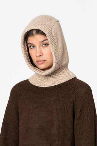 Woman in front of white background wearing brown knit sweater and sand knit Alpaca wool Balaclava by Dinadi. 