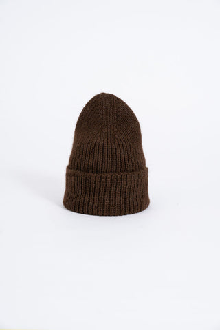 Brown coloured thick knit folded cuff toque in front of white background. 