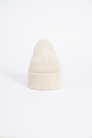 White coloured thick knit folded cuff toque in front of white background. 