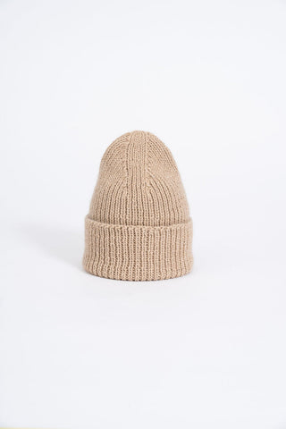 Sand coloured thick knit folded cuff toque in front of white background. 