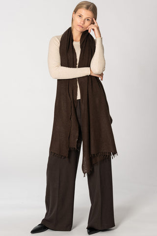 Woman wearing cream top, brown wide leg pants and brown cashmere scarf draped over her shoulders. 