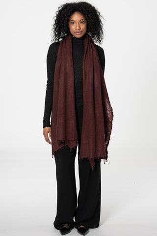Woman wearing black turtleneck, black pants and wine red cashmere scarf draped over her shoulders. 