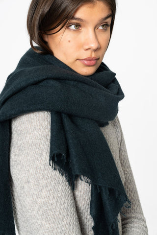 Woman wearing grey sweater and teal green cashmere scarf wrapped around her shoulders, 