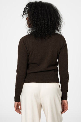 Back view of woman in front of white background wearing dark brown yak wool knit cardigan by Dinadi paired with cream trousers. 