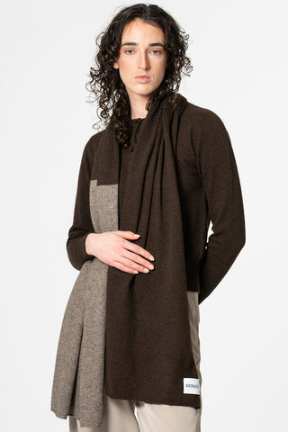 Woman in front of white background wearing dual colour (brown and oatmeal) scarf by Dinadi. 