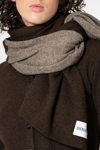 Woman in front of white background wearing brown cardigan and dual colour (brown and oatmeal) scarf by Dinadi double wrapped around her neck. 