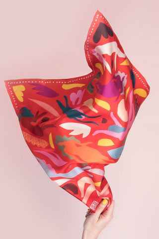 Colorful scarf with abstract design held against a pink background