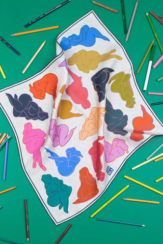 White silk scarf with colourful images of woman on a green background. 