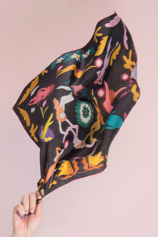 Colorful patterned fabric held against a pink background