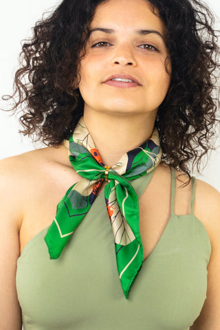 Woman with green one-shoulder top wearing green silk neckerchief scarf tied aroundher neck. 