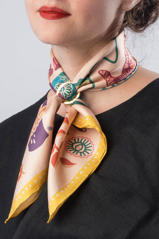 Close-up of woman wearing pink and yellow multicolour printed neckerchief tied around her neck. 