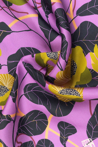 Close-up of Dora Nola scarf with black and yellow flowers on pink background. 