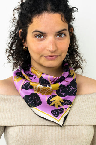 Woman wearing pink, black and yellow floral print scarf tied around neck like a bandanna. 