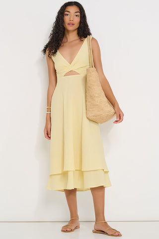 Woman wearing a light yellow stripe dress with cut-out detail against a white background. 