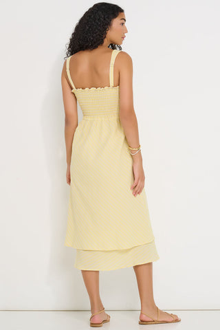 Back view of woman wearing a light yellow stripe dress against a white background. 