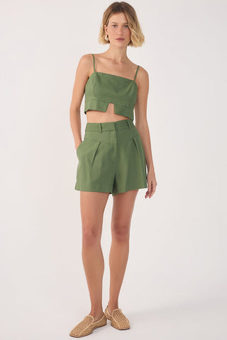 Woman wearing green cropped tank top with cut-out detail and matching pleated green shorts. 